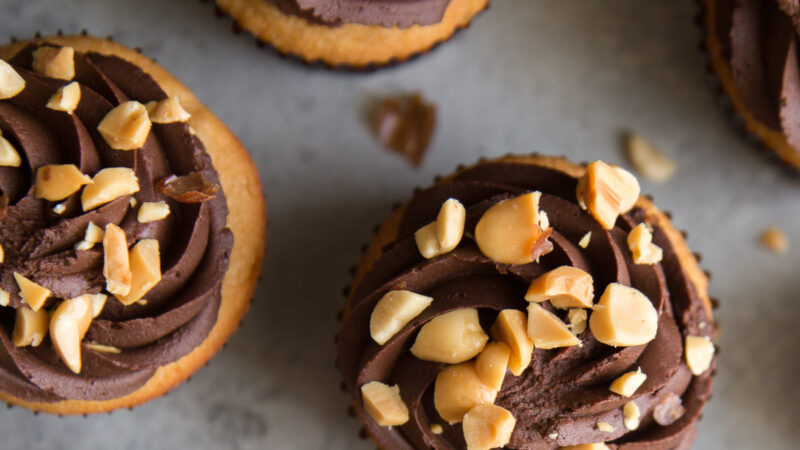 peanut butter cupcakes frosted with whipped chocolate ganache and topped with chopped peanuts.