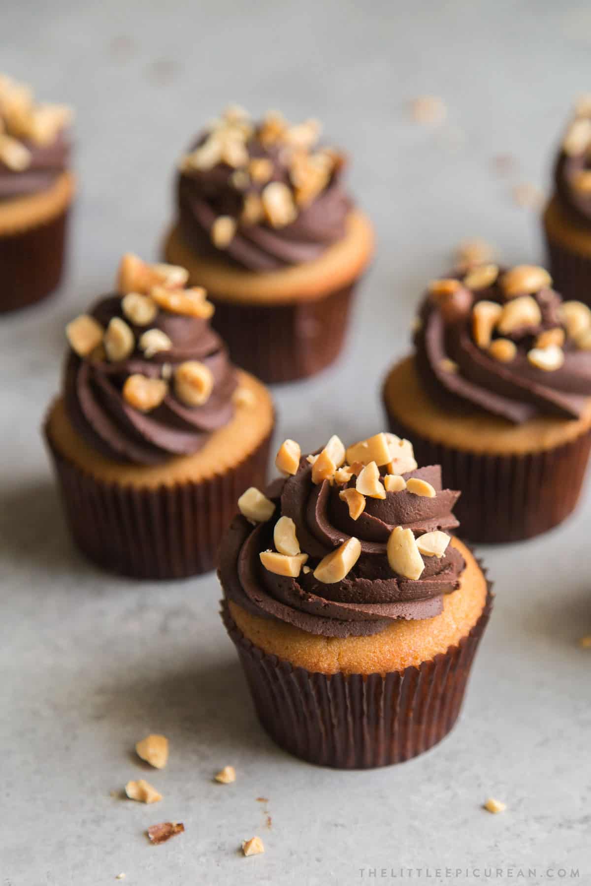 peanut butter cupcakes frosted with whipped chocolate ganache and topped with chopped peanuts.