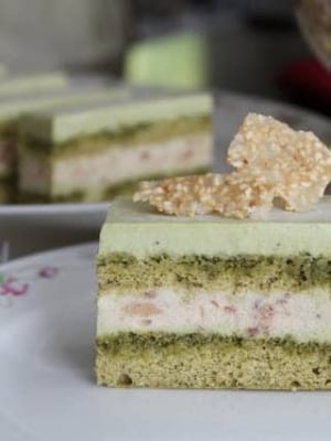 a slice of matcha red bean mousse cake on decorative white tea plate.