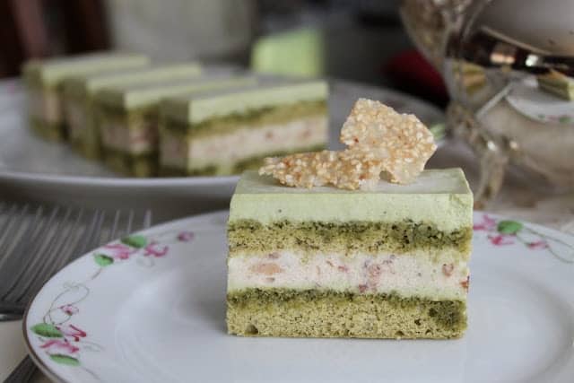 a slice of matcha red bean mousse cake on decorative white tea plate.