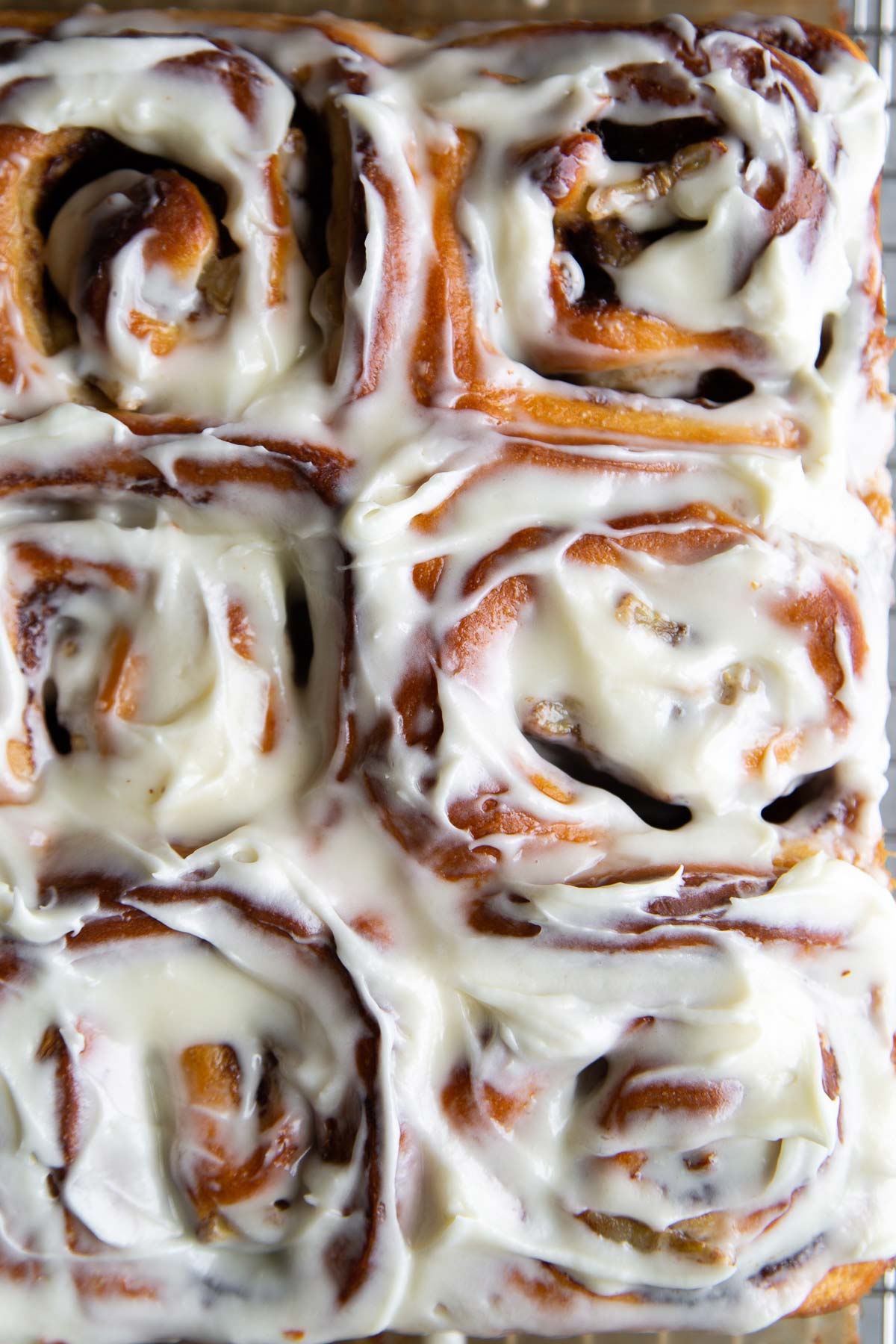 banana cinnamon rolls frosted with cream cheese glaze in baking pan.
