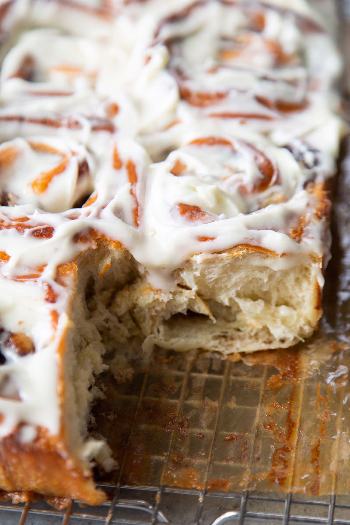 banana cinnamon rolls with cream cheese glaze on wire rack.