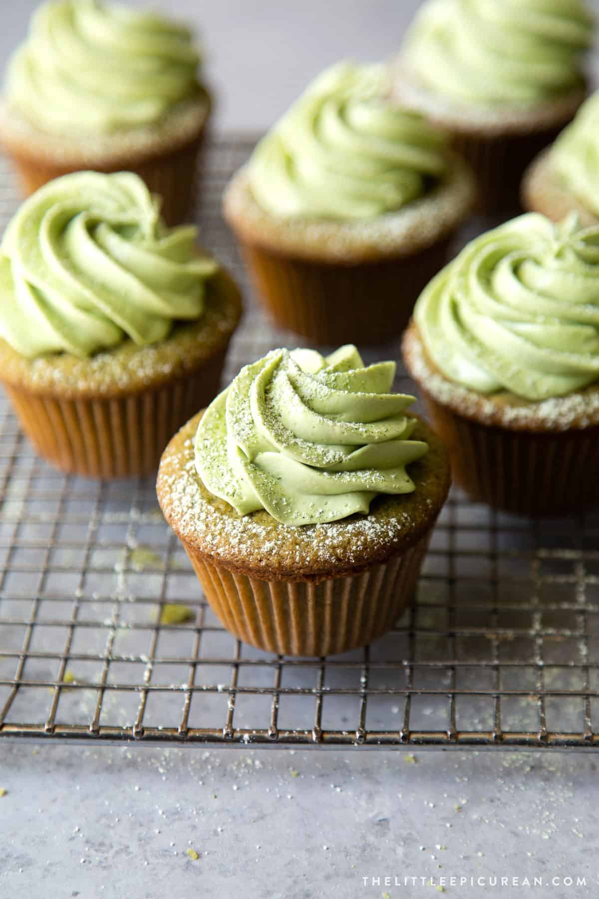 matcha cupcakes filled with sweetened red bean and frosted with matcha buttercream on wire cooling rack.