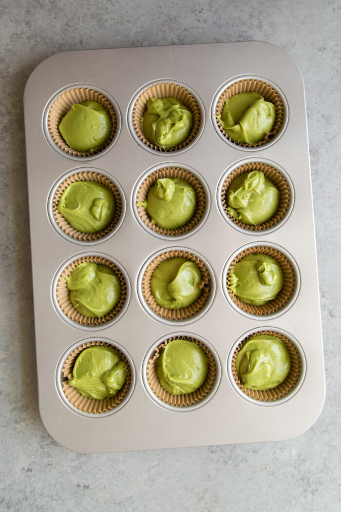 matcha cupcake batter distributed in lined muffin tin.