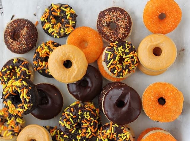 Baked mini halloween donuts topped with a variety of festive sprinkles.