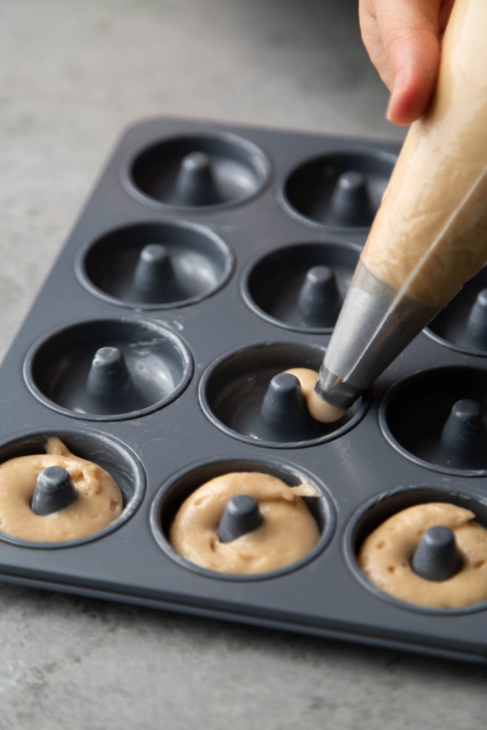 use piping bag to fill prepared donut pans with batter.