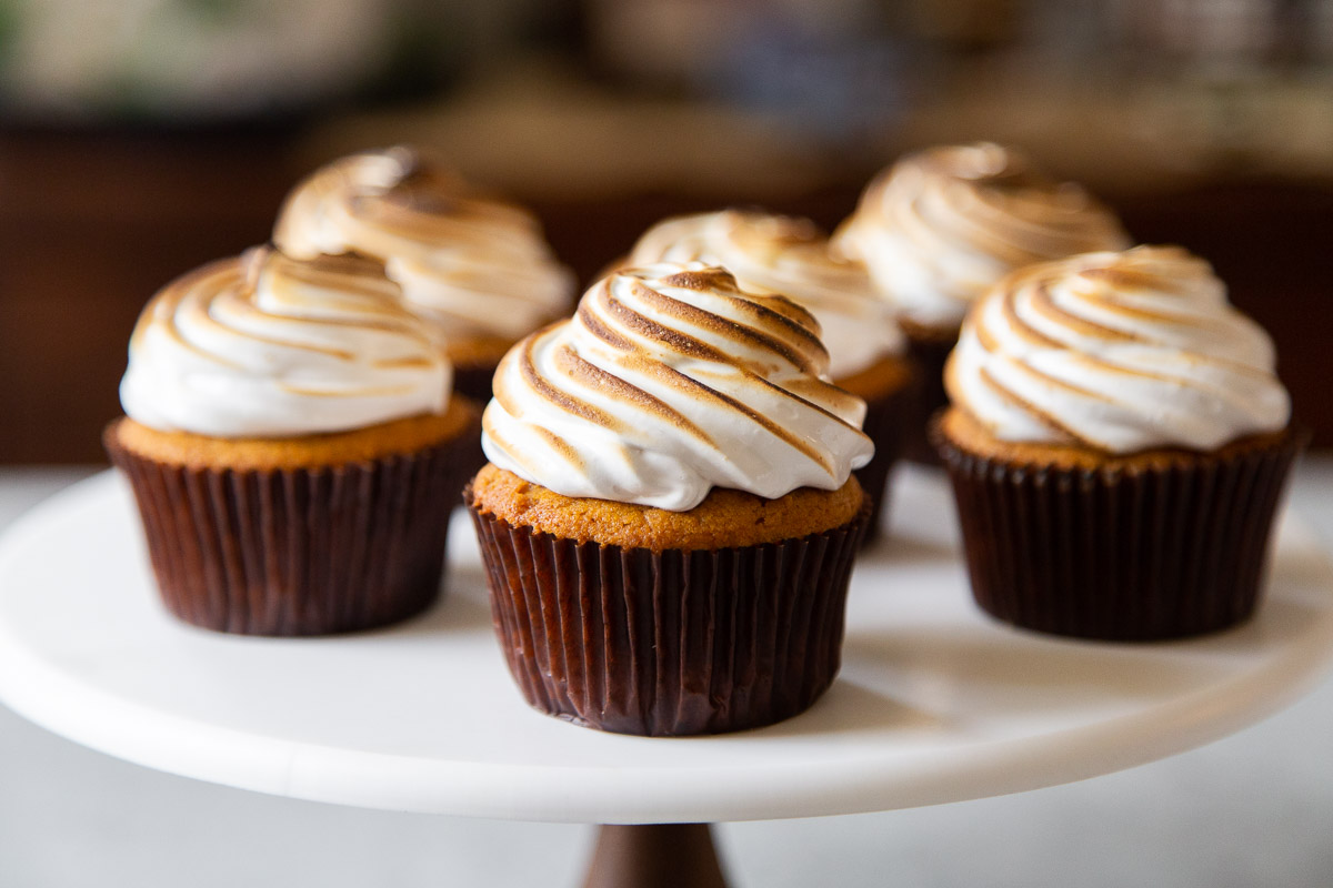 six sweet potato cupcakes with toasted marshmallow meringue frosting on cake stand.