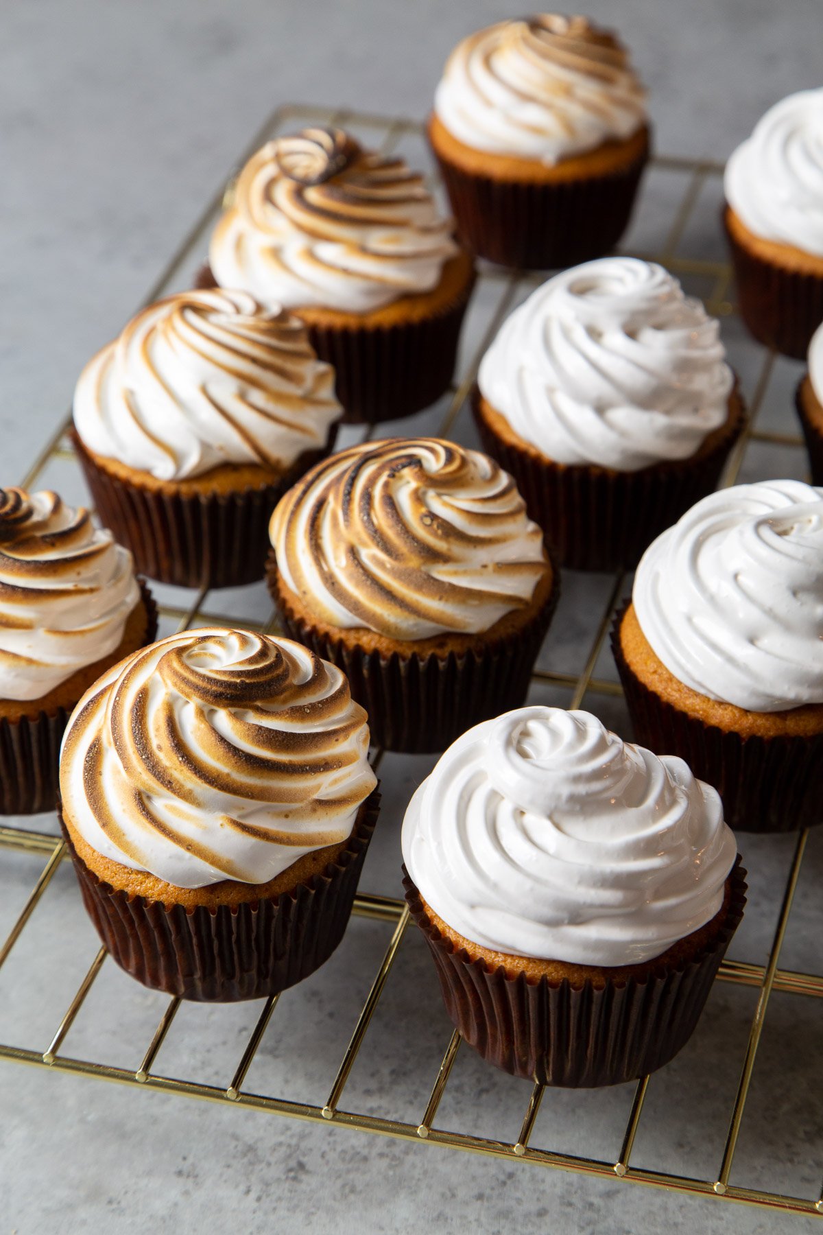 sweet potato cupcakes on gold wire cooling rack, some cupcakes have toasted meringue topping.