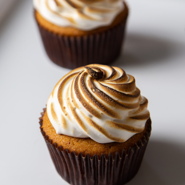 sweet potato cupcake with dark paper wrapper topped with toasted marshmallow meringue.