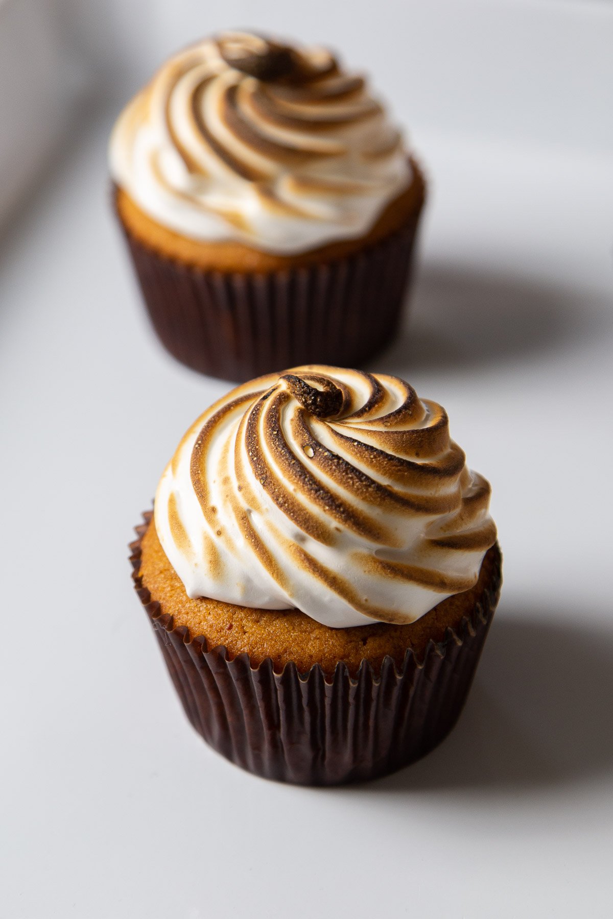 sweet potato cupcake with dark paper wrapper topped with toasted marshmallow meringue.