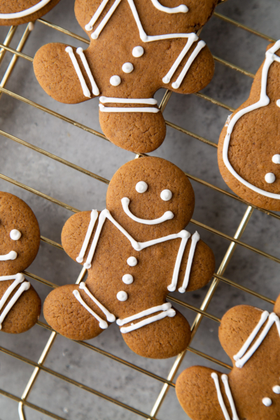 gingerbread person decorated with white royal icing on gold cooling rack.