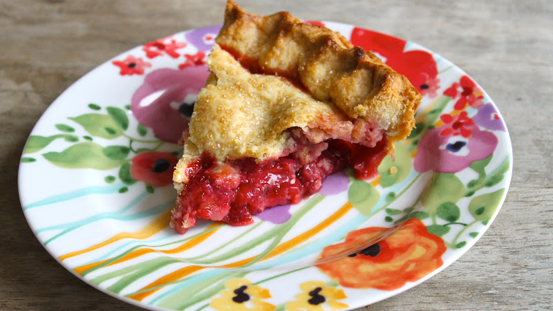 slice of strawberry pie on decorative floral plate.