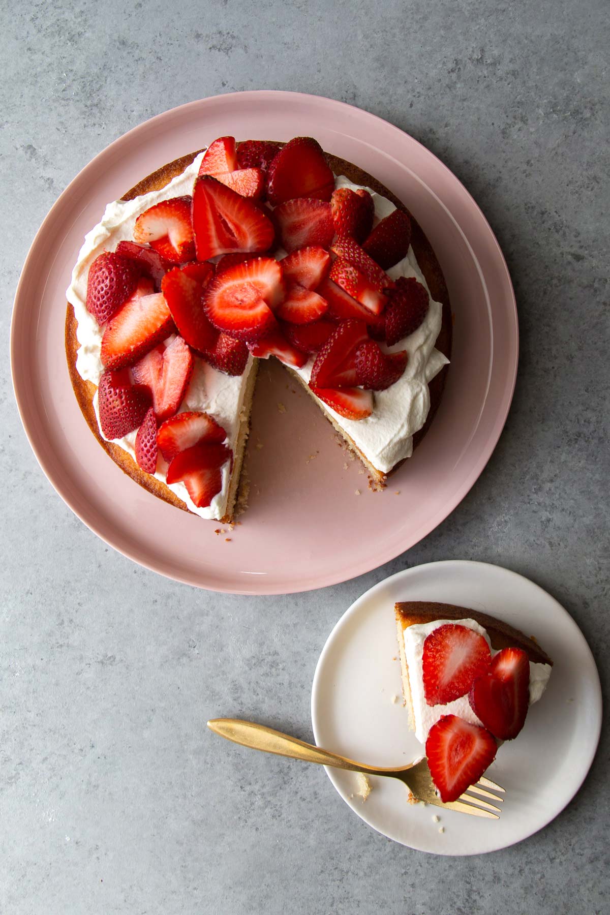 strawberry almond cake on pink serving plate plus cake slice on white plate. 