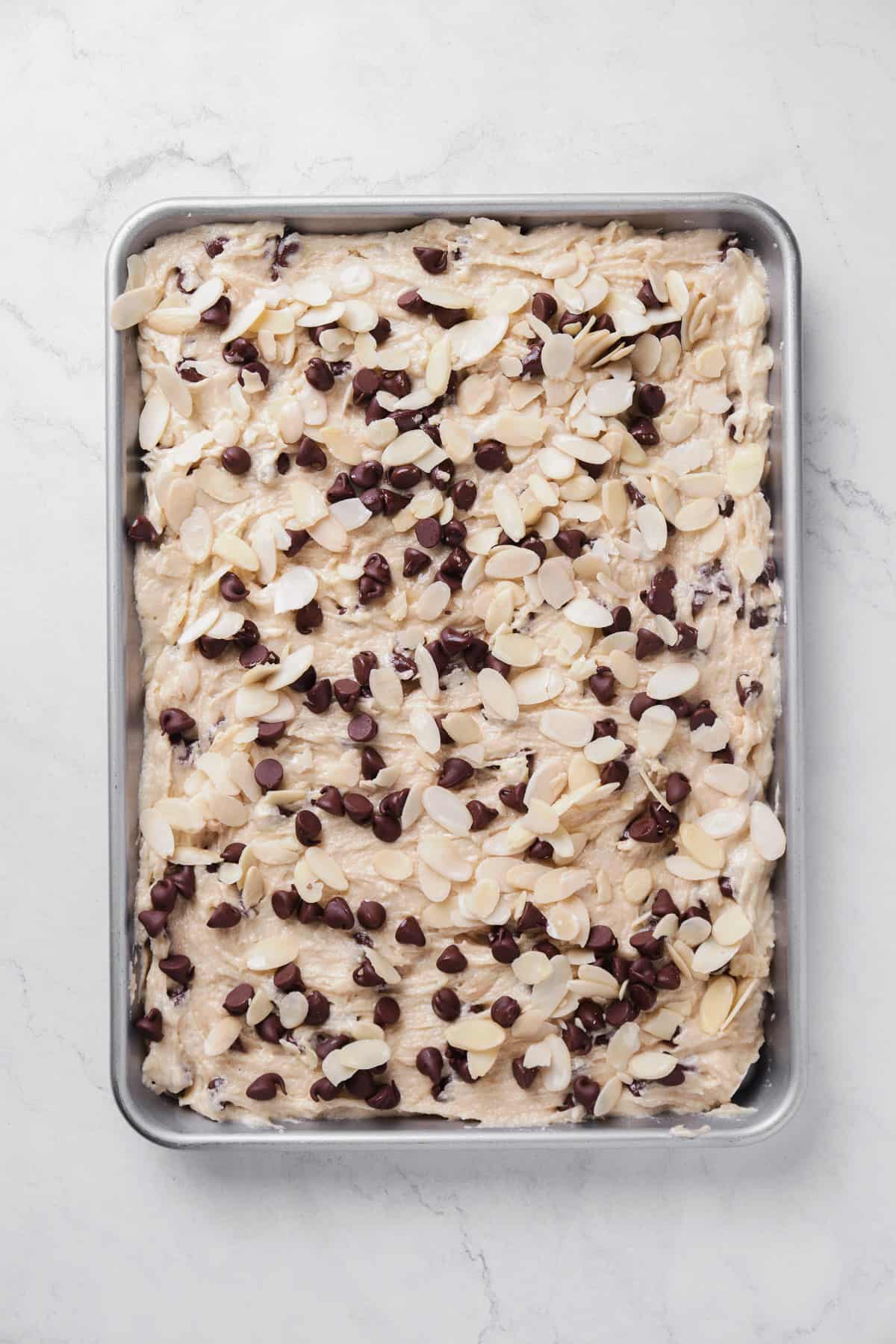 spread dough into prepared sheet pan and top with additional chocolate chips and sliced almonds.