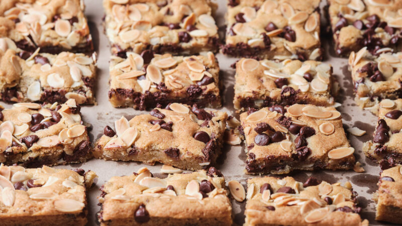 almond chocolate chip cookie bars arranged on parchment paper.