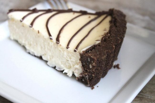 slice of spider web cheesecake tart on white plate.