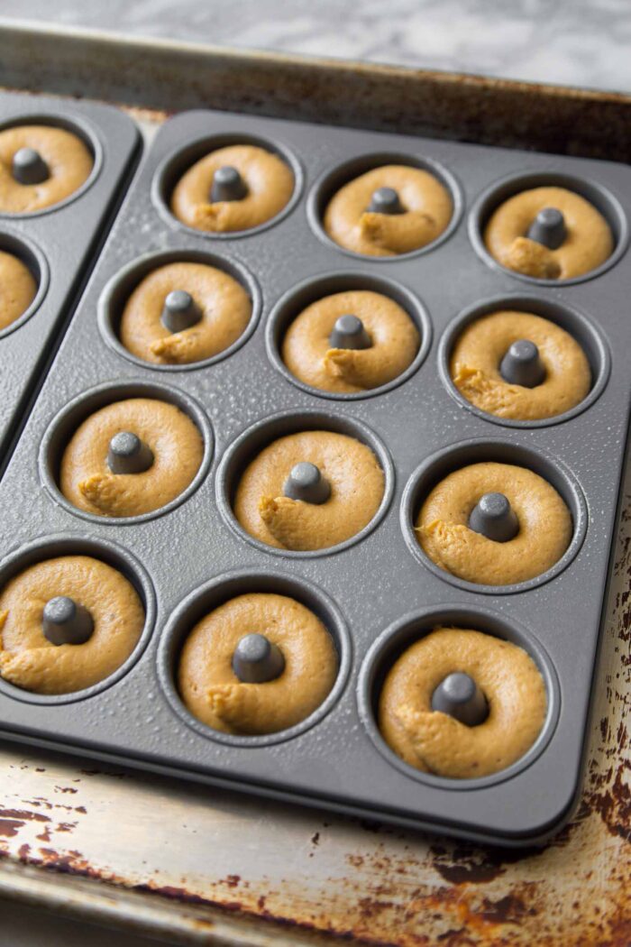 piped pumpkin batter in mini donut pans.