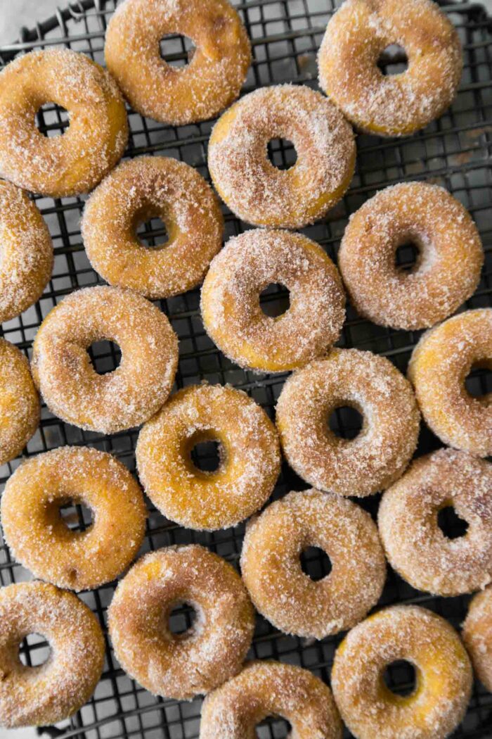 cinnamon sugar pumpkin donuts on black wire rack.