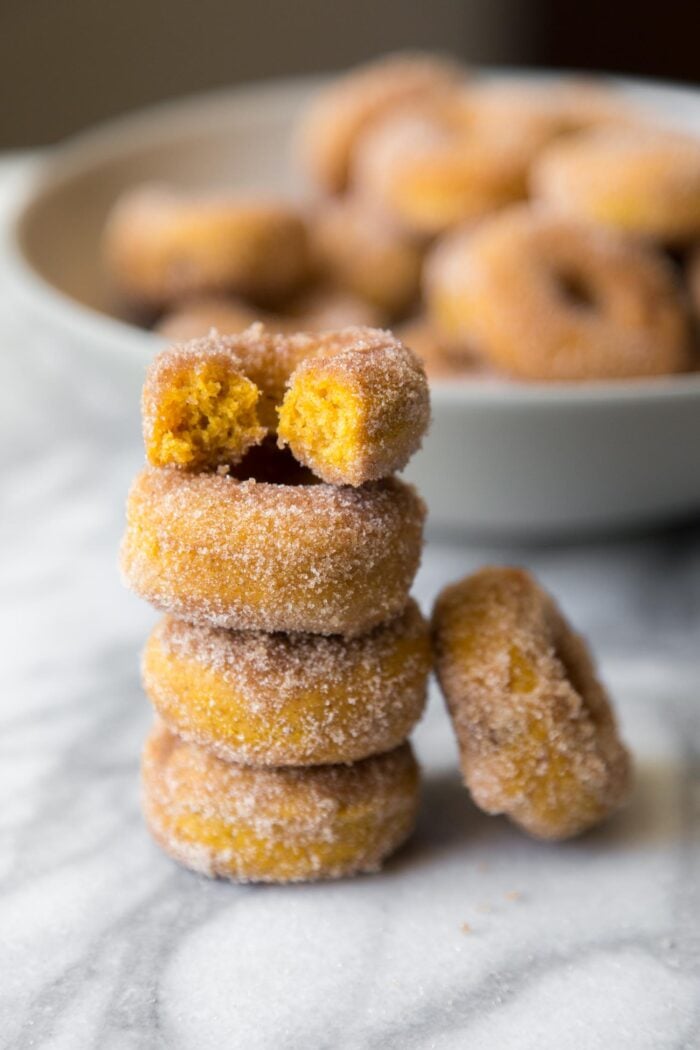 stacked baked mini pumpkin donuts on marble table.