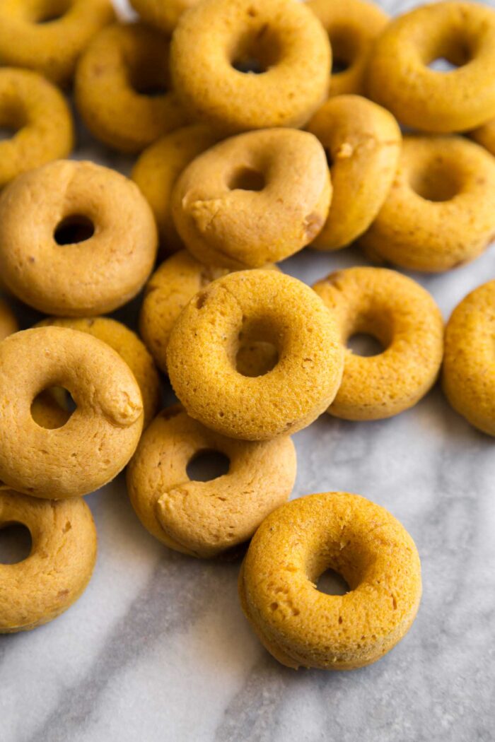 baked mini pumpkin donuts on marble table.