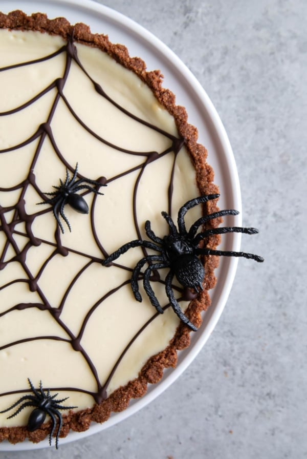 chocolate spider web cheesecake tart decorated with plastic spiders.