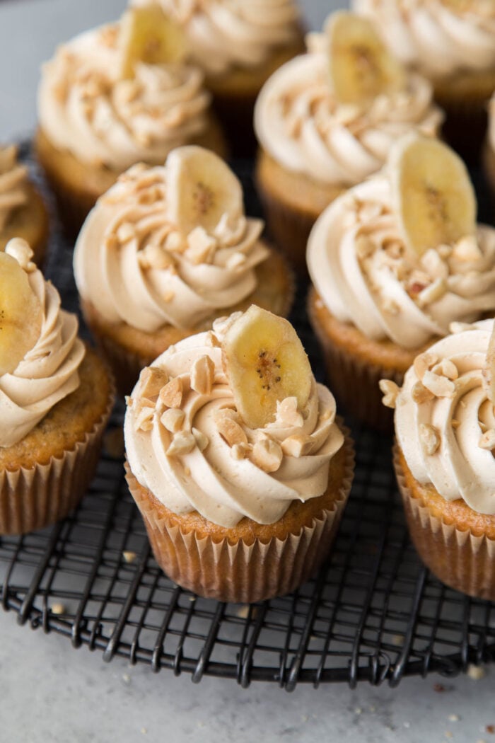 banana cupcakes with peanut butter frosting on black wire cooling rack.