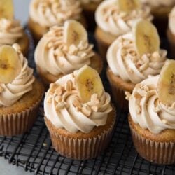 banana cupcakes with peanut butter frosting on black wire rack.