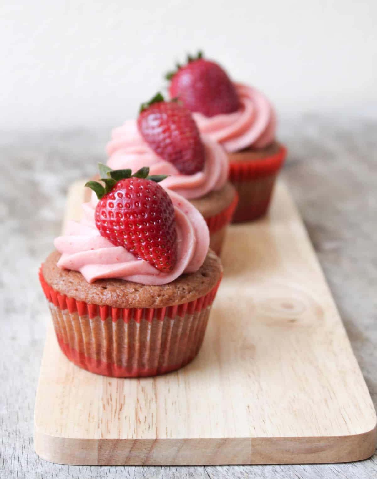 strawberry cupcakes topped with strawberry cream cheese and garnished with fresh strawberry. 