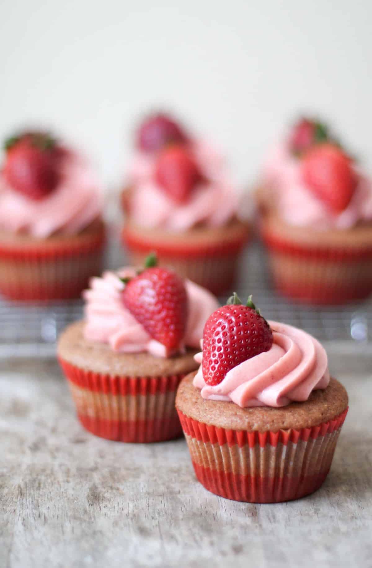 strawberry cupcakes topped with strawberry cream cheese and garnished with fresh strawberry. 