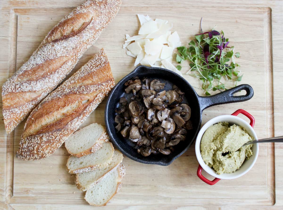 leek pesto crostini components on wooden cutting board. 