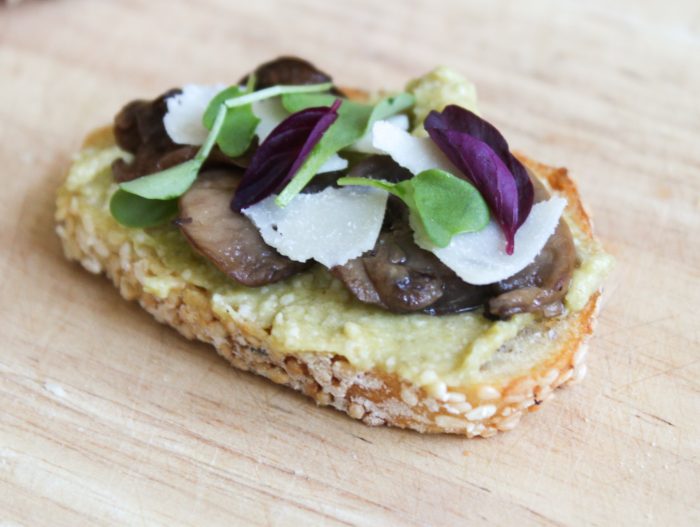 Leek pesto crostini topped with roasted mushrooms, shaved parmesan, and micro-greens