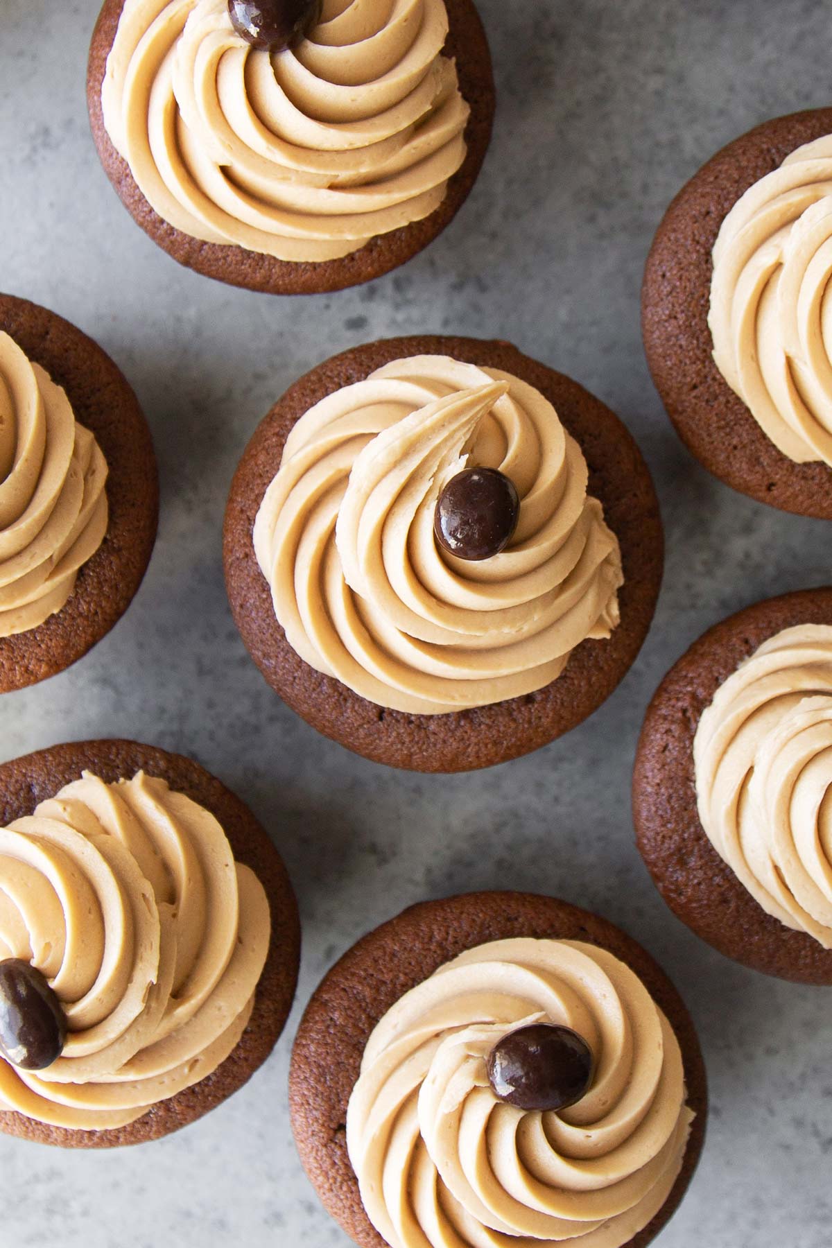 overhead of mocha cupcakes with coffee frosting and chocolate covered coffee bean.