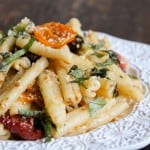 roasted tomato and pasta piled up on white plate.