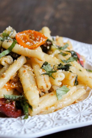 roasted tomato and pasta piled up on white plate.