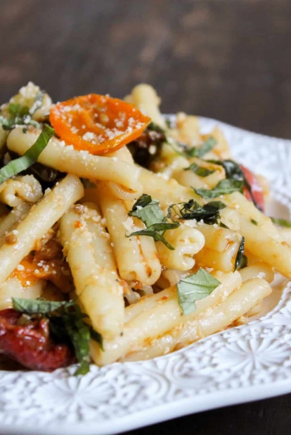roasted tomato and pasta piled up on white plate.