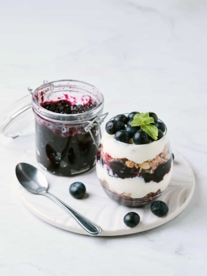 refrigerator blueberry jam along side layered parfait made with yogurt, granola, and blueberry jam.