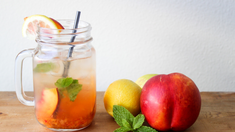 nectarine smash cocktail served in mason jar along side fresh fruit.