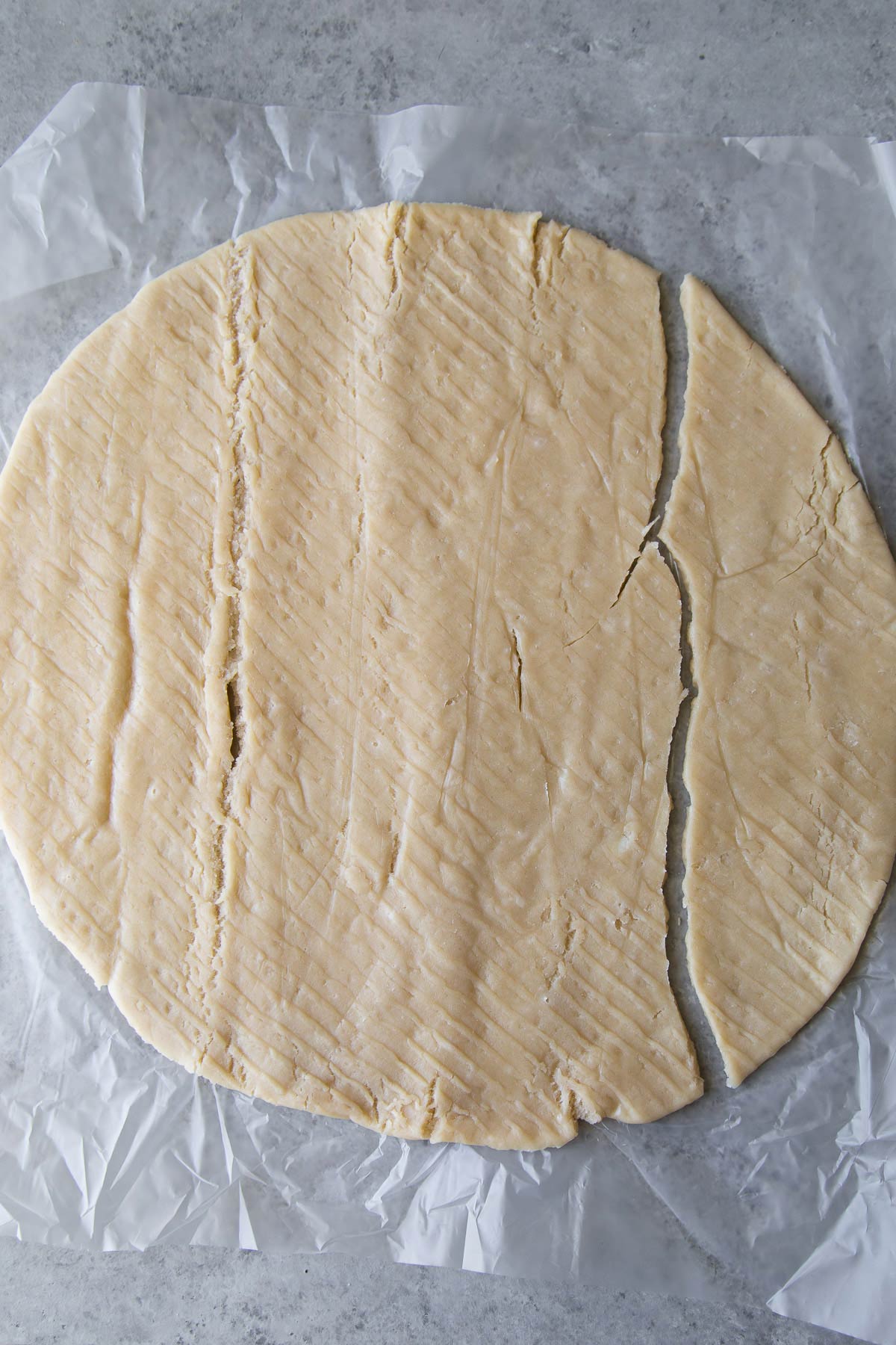unrolled frozen pie dough with cracks and splits.