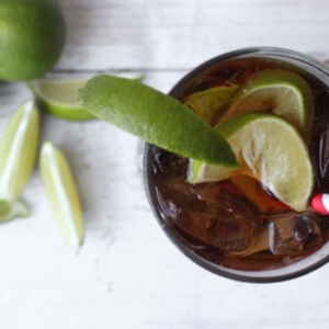 overhead shot of cuba libre cocktail featuring rum, coke, and lime.