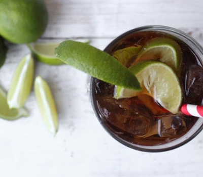 overhead shot of cuba libre cocktail featuring rum, coke, and lime.