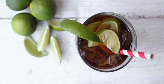 overhead shot of cuba libre cocktail featuring rum, coke, and lime.