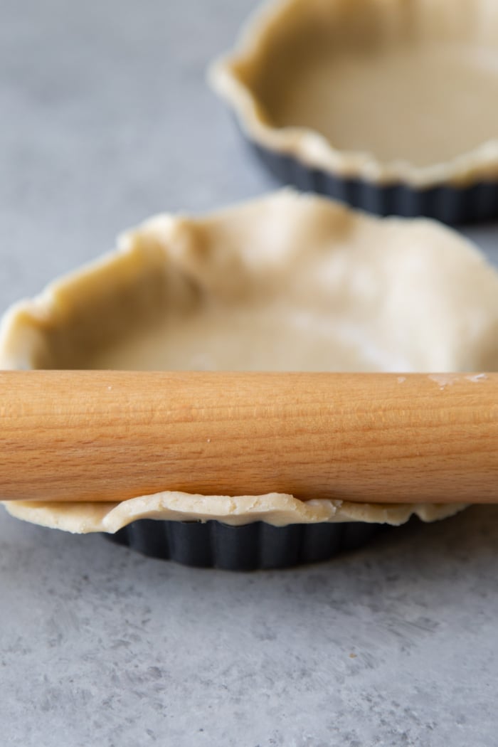 use a rolling pin to remove excess dough from tart shell pan.