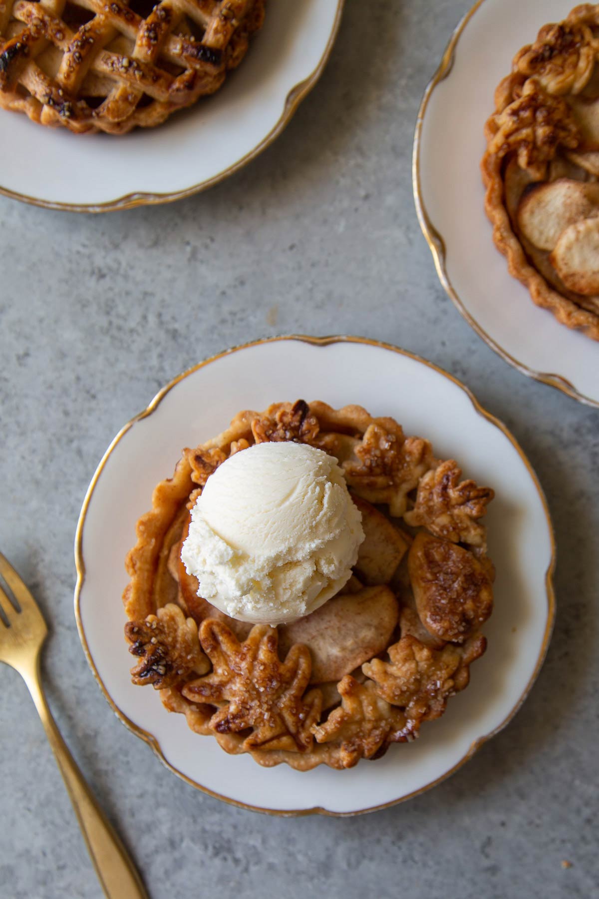 mini apple tarts on dessert plate served with scoop of vanilla ice cream.