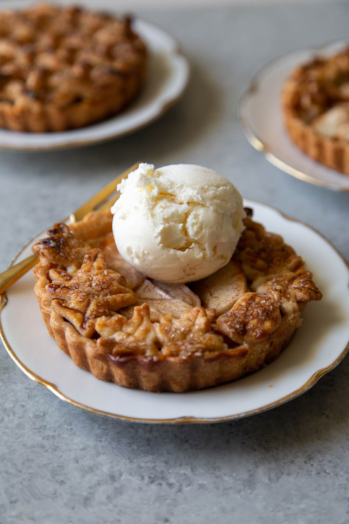 mini apple pie tart on serving plate with a scoop of vanilla ice cream.