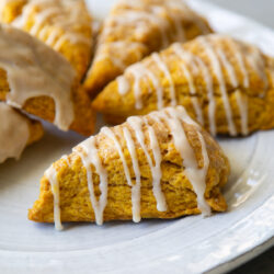 close up of pumpkin scone with maple glaze on serving plate.