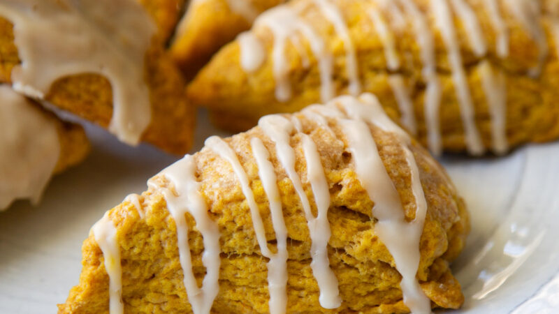 close up of pumpkin scone with maple glaze on serving plate.