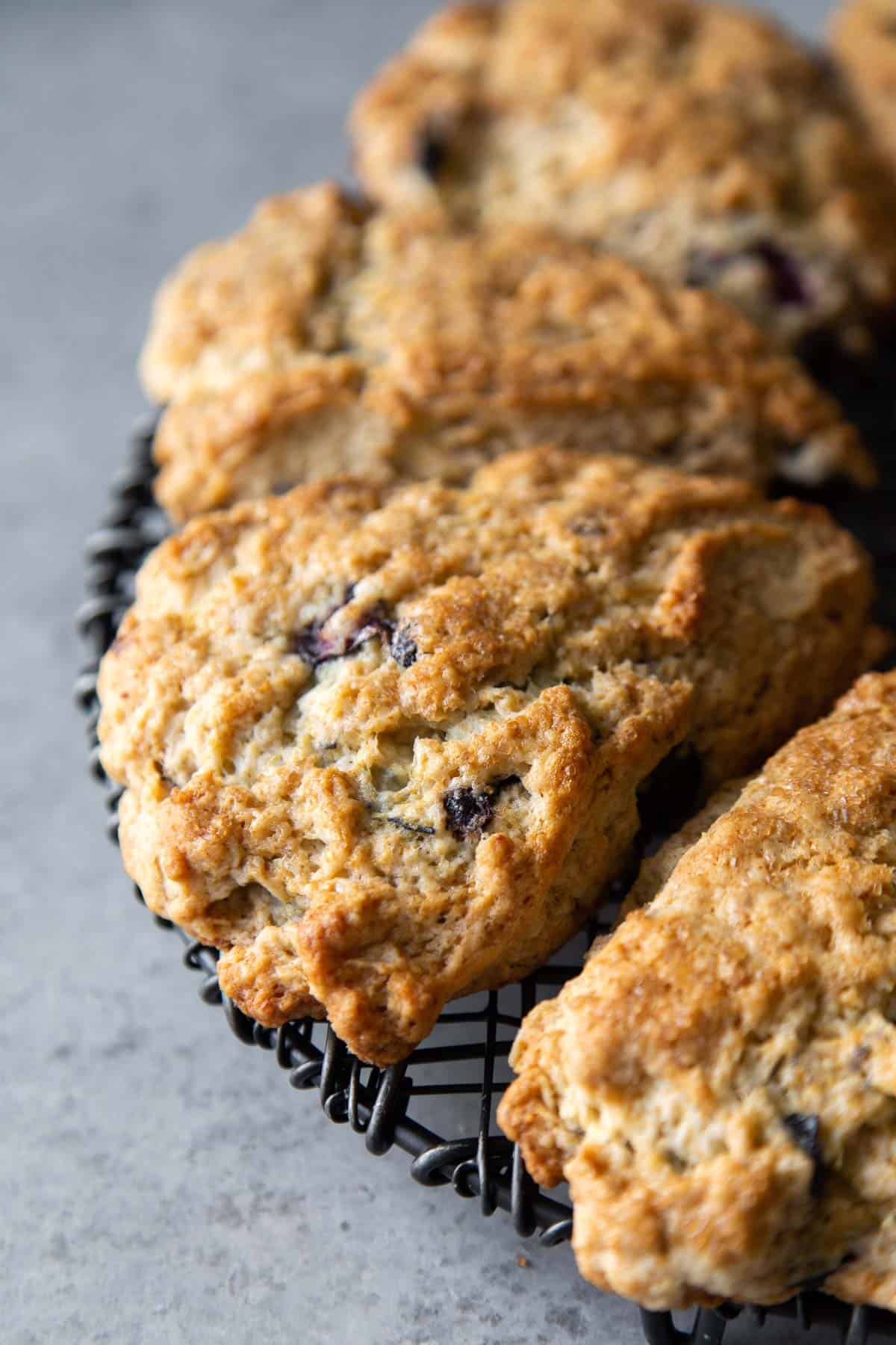 close up of lemon blueberry scones on black wire rack.