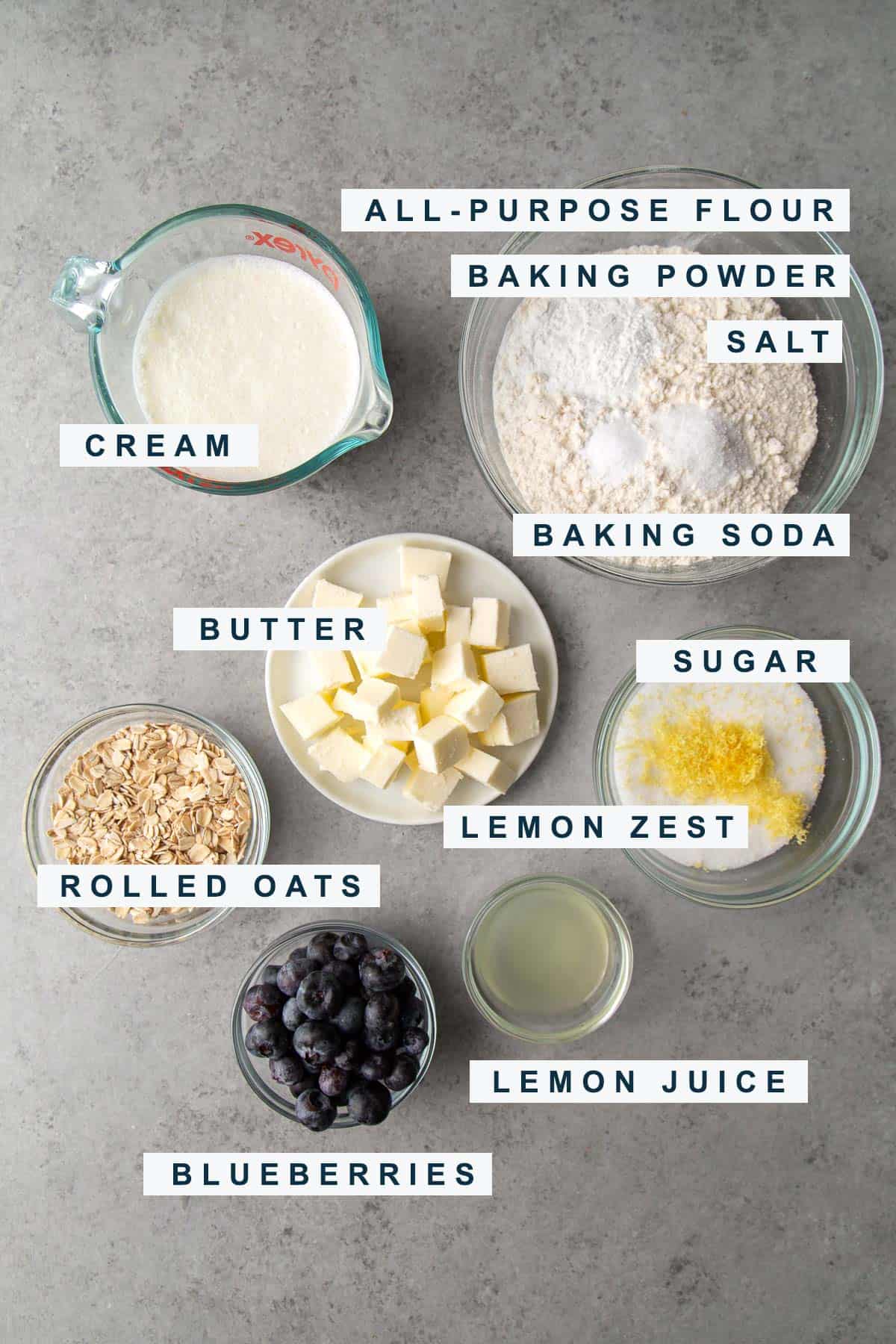 portioned out ingredients for lemon blueberry scones include flour, sugar, butter, cream, and baking powder. 