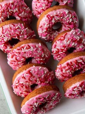 tray of valentine pink cake donuts with festive sprinkles.