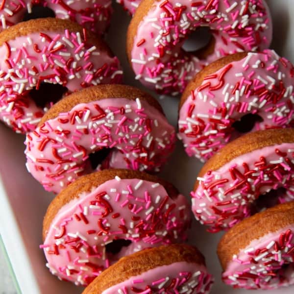 tray of valentine pink cake donuts with festive sprinkles.